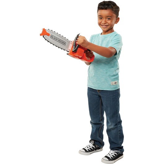 Chainsaw being held by a person standing and smiling.