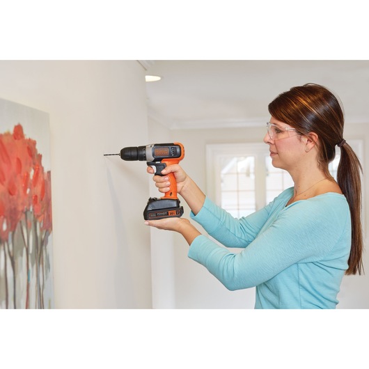 Cordless Drill Driver being used by person to drill hole in wall.