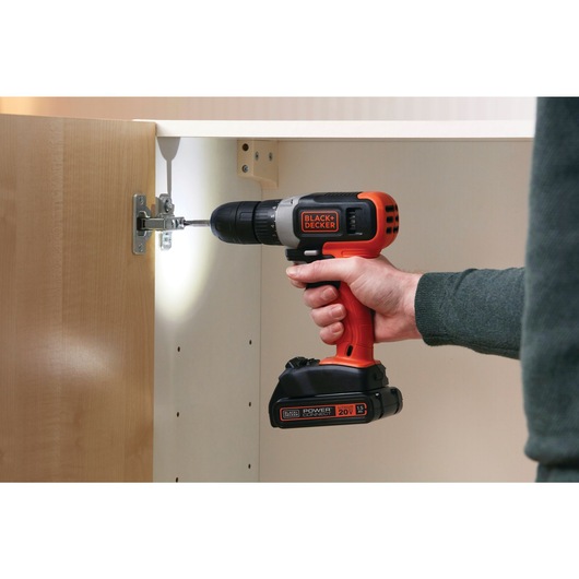 20 volt MAX cordless drill driver being used by a person to fix a cabinet door.
