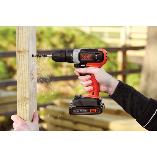 Cordless drill and driver being used to drill into a wooden pillar.