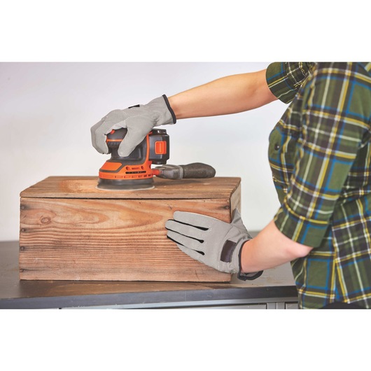 20 volt MAX cordless random orbital sander being used by a person to sand wooden box.