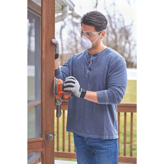 20 volt MAX cordless random orbital sander being used by a person to sand wooden door.