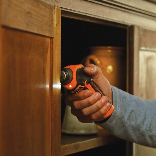 Lithium Rechargeable Screwdriver being used on wood cabinet with LED light illuminating work surface.