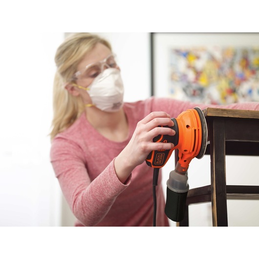5 inch Random Orbital Sander being used by person to smooth out edges of wooden furniture.