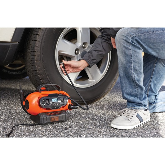 MAX Multi Purpose Inflator being used by person to inflate car tire.