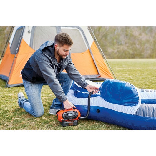 Multi Purpose Inflator being used by person to inflate campsite furniture.