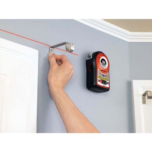 Bulls Eye auto leveling laser with AnglePro being used by a person to hang door attachment on wall.