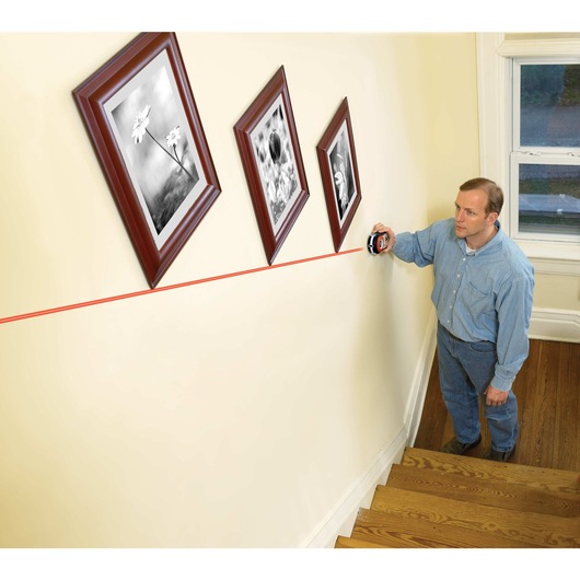 Bulls Eye Auto Leveling Laser with Angle Pro being used for hanging photo frames diagonally in stairs.