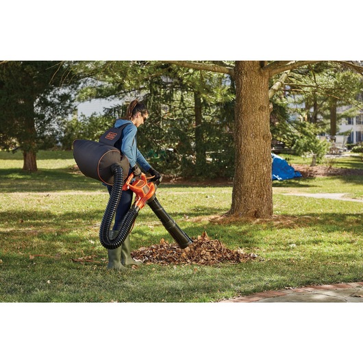 3 in 1 VACPACK 12 Ampere leaf blower, vacuum, and mulcher being used by a person to pick up leaves.
