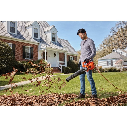 9 Amp Electric Axial Leaf Blower being used to blow leaves by a person.