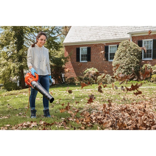 9 Amp electric axial leaf blower being used by a person to remove leaves from yard.