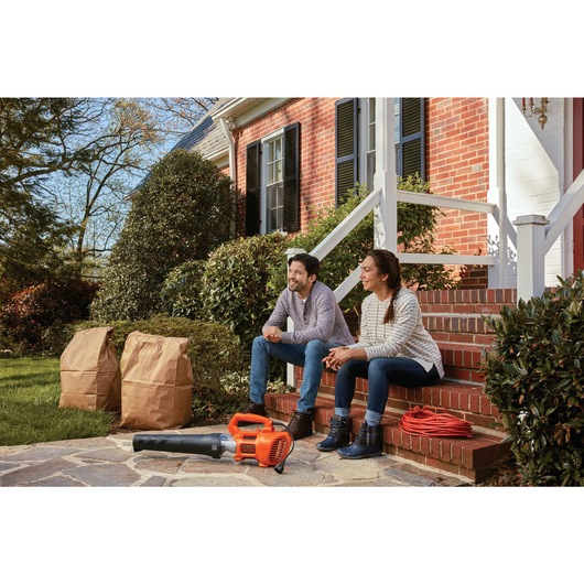 9 Amp electric axial leaf blower on floor with a couple sitting on stairs.