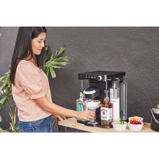 woman, on the patio, placing her ice filled margarita glass onto the bev by BLACK+DECKER™ cocktail maker