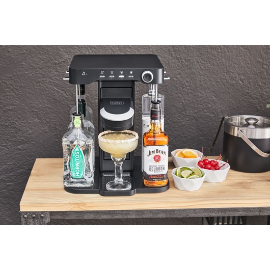 bev by BLACK+DECKER™ cocktail maker with a freshly made margarita on an outdoor wooden serving table with an ice bucket and assorted garnishes