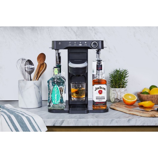 bev by BLACK+DECKER™ cocktail maker on a marble kitchen counter with a freshly made old fashioned on the glass shelf admist kitchen utensils and décor