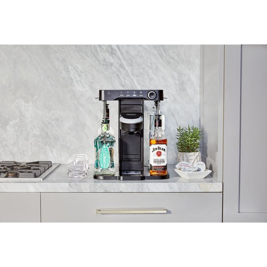 bev by BLACK+DECKER™ cocktail maker on a marble kitchen counter with assorted capsules and glassware