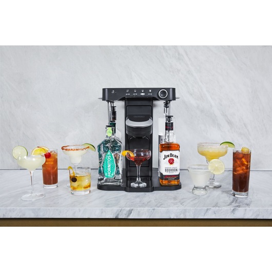 bev by BLACK+DECKER™ cocktail maker  on a marble kitchen counter with an assortment of garnished drinks