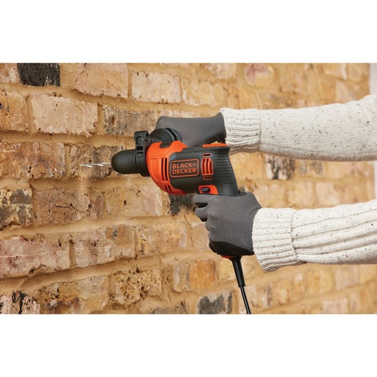 6 and 5 tenths Amp half inch Hammer Drill being used by person to drill hole in brick wall.