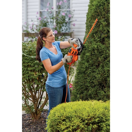 16 inch electric hedge trimmer being used by a person to trim a hedge.