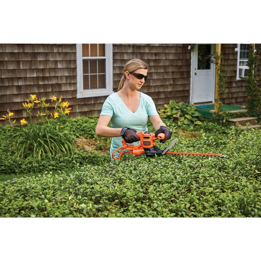 16 inch SAW BLADE Electric Hedge Trimmer being used for trimming bushes by person.