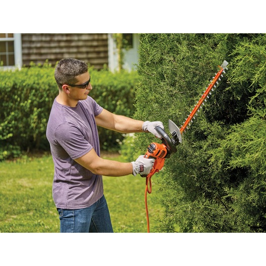 20 inch SAW BLADE electric hedge trimmer being used by a person to trim hedge.