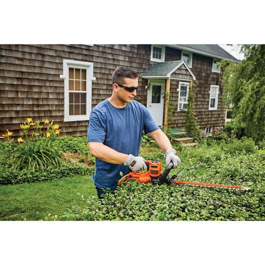 20 inch SAWBLADE electric hedge trimmer being used by a person to trim hedge.