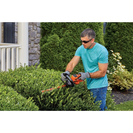 20 inch saw blade electric hedge trimmer being used by a person.