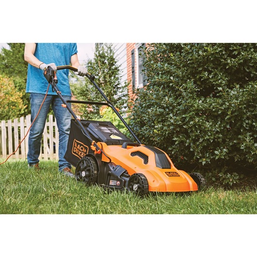 Corded electric lawn mower cutting grass.
