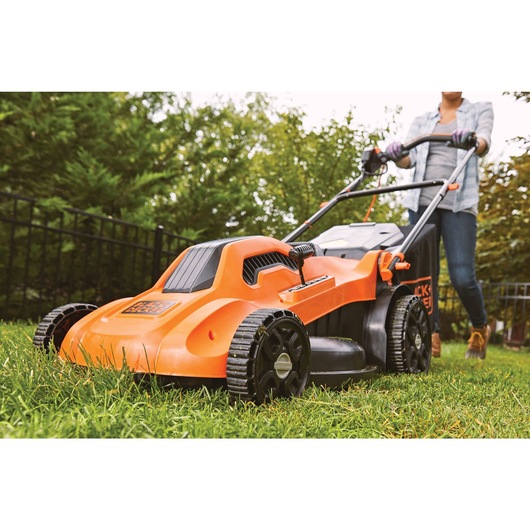 13 ampere 20 degree corded electric lawn mower being used to cut grass.