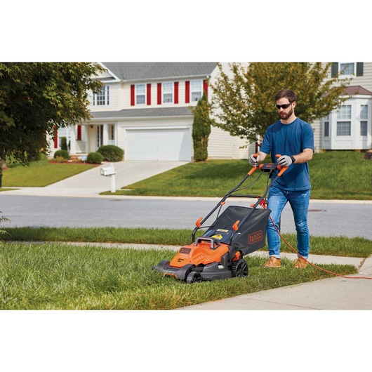 10 ampere 15 inch electric lawn mower with comfort grip handle being used by a person.