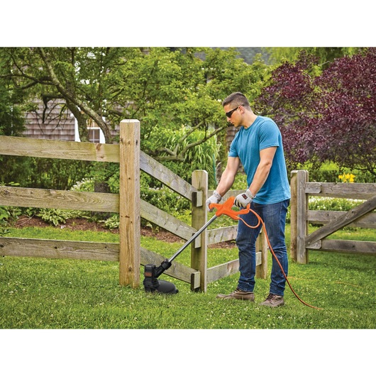 4 Amp 13 inch Electric String Trimmer being used by person to trim grass.