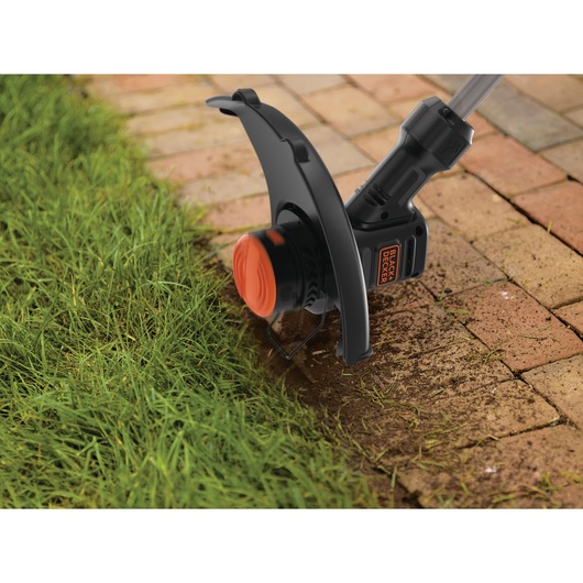 4 AMP 13 inch Electric String Trimmer being used on grass edge.