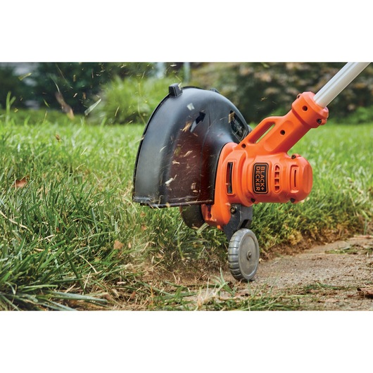 Electric string trimmer / edger trimming grass.