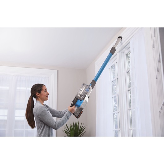 Power Series extreme cordless stick vacuum cleaner being used by a person to clean hard to reach area.

