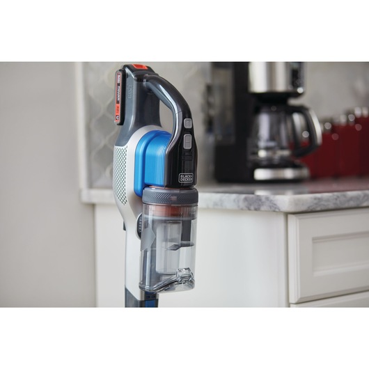 POWER SERIES Extreme Cordless Stick Vacuum Cleaner standing in upright position beside kitchen shelf.