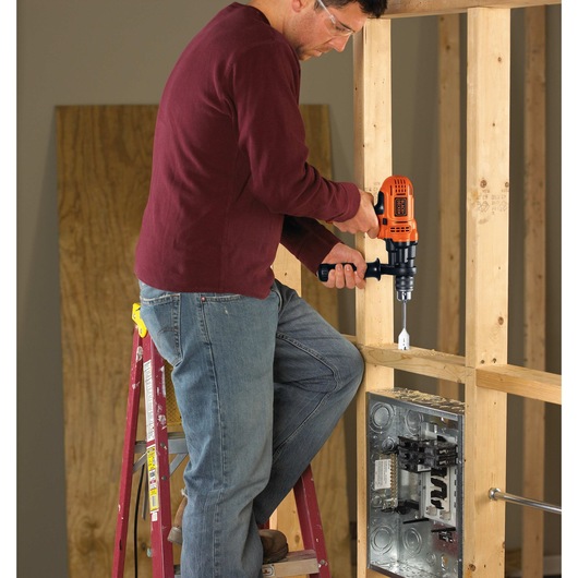 7 Amp half inch drill driver being used by a person to drill a hole in wooden frame.