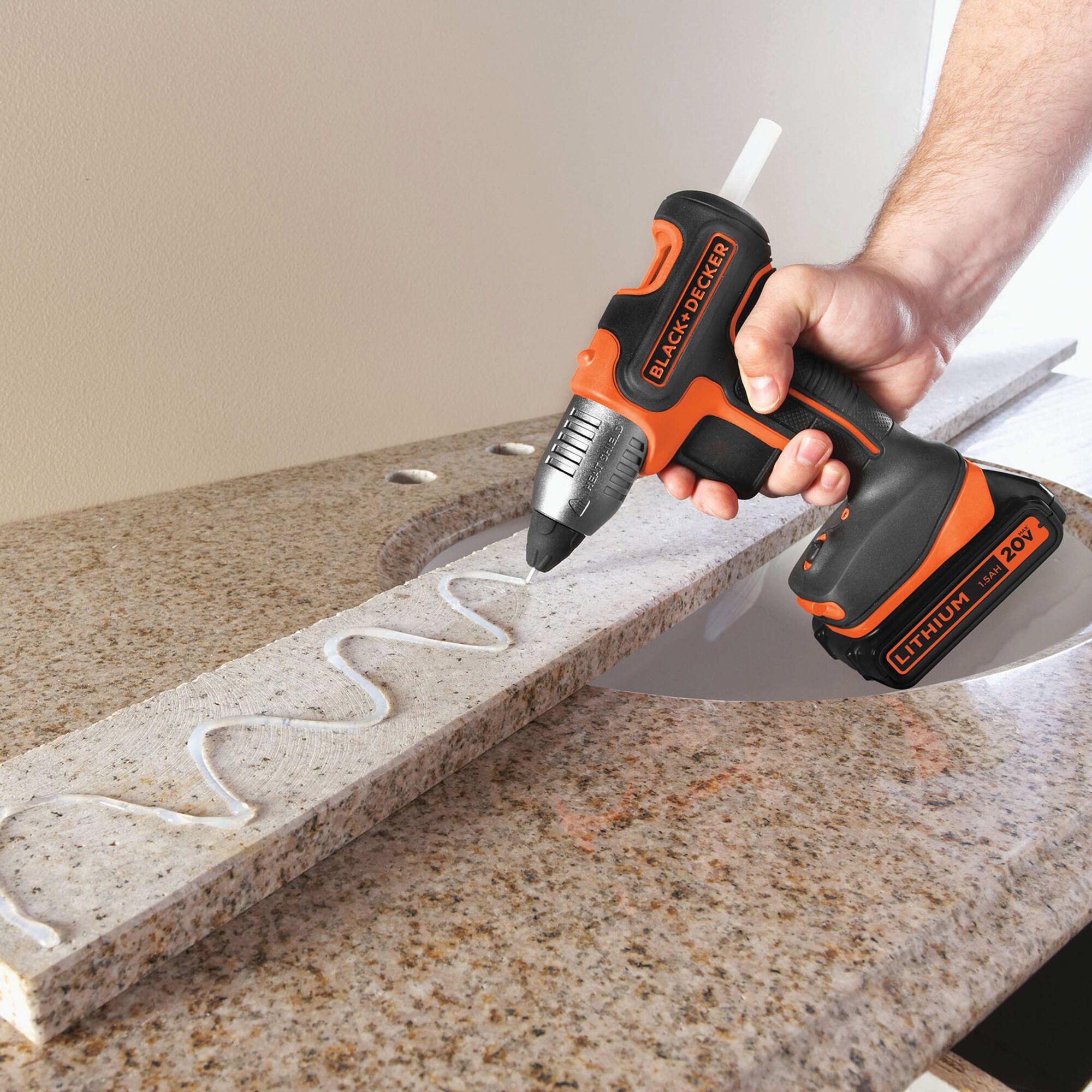 Cordless Glue Gun being used to lay long lines of glue on strip of wood.