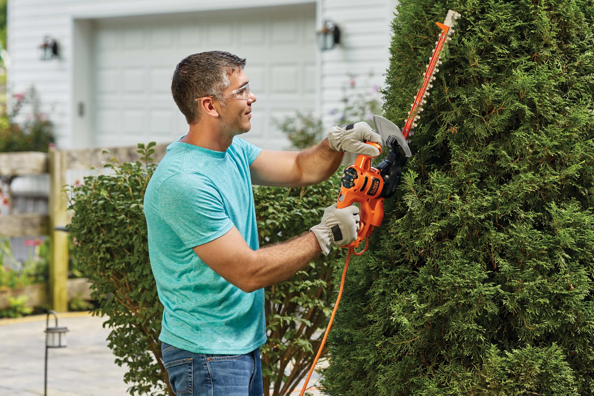 16 inch saw blade electric hedge trimmer being used to trim a tree by a person.