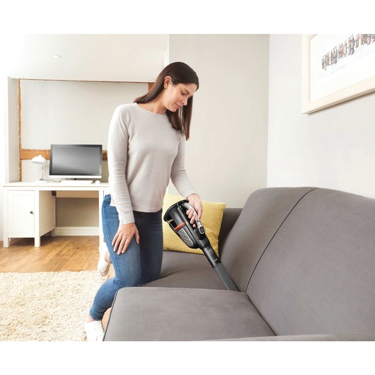 20 volt MAX dustbuster Advanced Clean cordless hand vacuum being used by a person to clean couch.