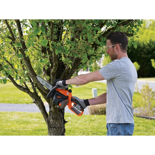 20 volt MAX lithium 10 inch chainsaw being used by a person to prune branches.