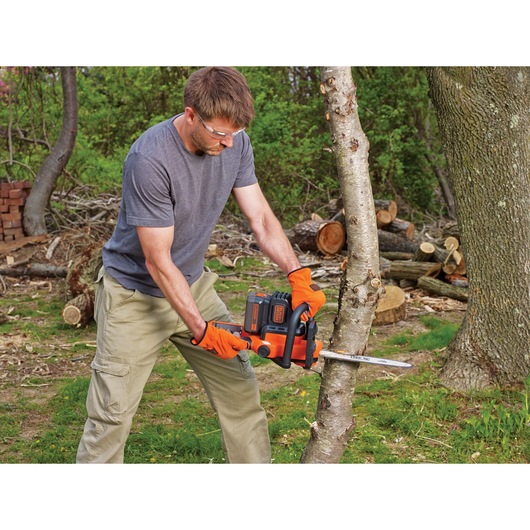 40 volt MAX Lithium 12 inch Chainsaw being used to cut down a tree by a person.