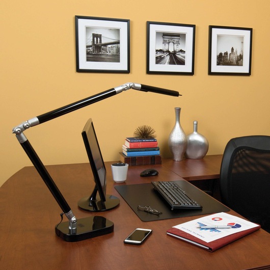 Ultra reach LED desk lamp being placed on a wooden work station.