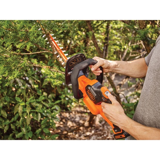 20 volt MAX lithium 22 inch POWERCUT hedge trimmer being used by a person to trim hedge.