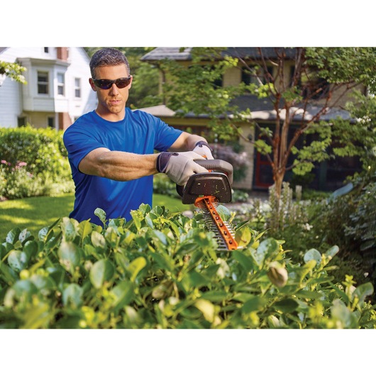 Lithium 22 inch POWER CUT Hedge Trimmer being used by person to trim bushes.