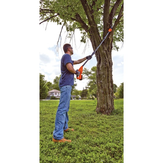 20 volt lithium pole pruning saw being used by a person.