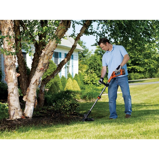 40 volt MAX cordless string trimmer with POWERCOMMAND being used by a person to trim grass outdoors.