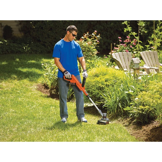 20 volt MAX lithium 12 inch trimmer edger being used by a person to trim grass.