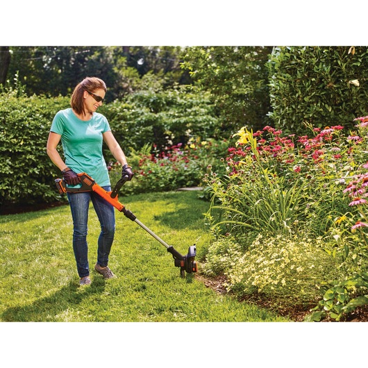 20 volt MAX Lithium EASYFEED String Trimmer / Edger  2 Lithium Ion Batteries  being used by a person outside on grass.