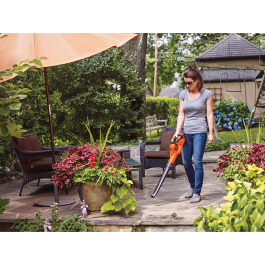 20 Volt Lithium POWER BOOST Sweeper being used by a person in a garden.
