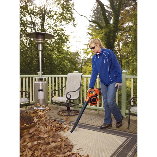 40 volt MAX Lithium Sweeper / Vacuum being used to vacuum fallen leaves on the ground by a person.